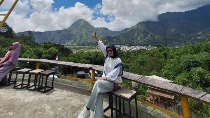 Foto : Pengunjung saat sedang berfoto di jembatan kaca Kebun Kopi, dengan panorama indah kaldera gunung purba Sembalun.