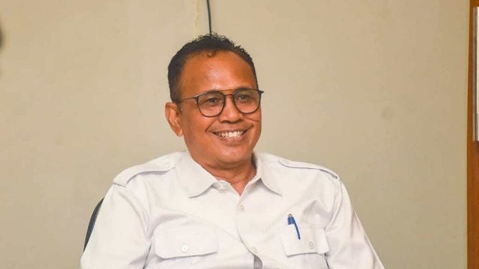 IMG-20260218-WA0020 Potret Kepala Dinas Kominfotik NTB, Ahsanul Halik, mengenakan kemeja putih formal dan kacamata, tampak tersenyum dalam sebuah pertemuan resmi.