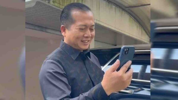 Gubernur NTB Lalu Muhamad Iqbal tersenyum saat melakukan video call melalui smartphone di depan kendaraan.