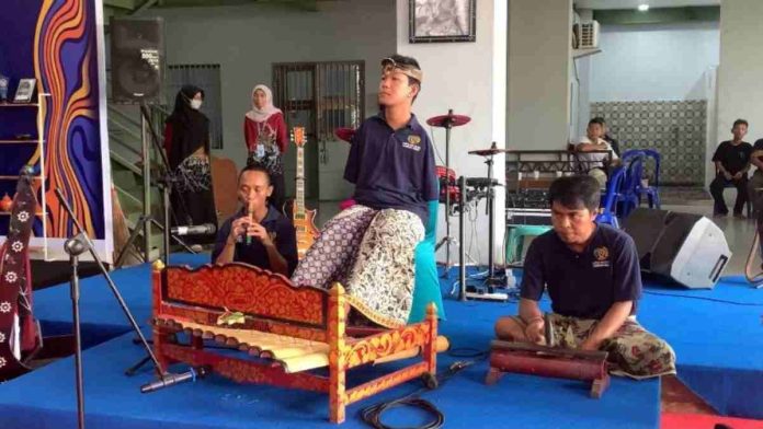 Agus Buntung bersama rekan warga binaan Lapas Lombok Barat sedang bermain musik tradisional gamelan di atas panggung dengan iringan suling dan alat musik lainnya.