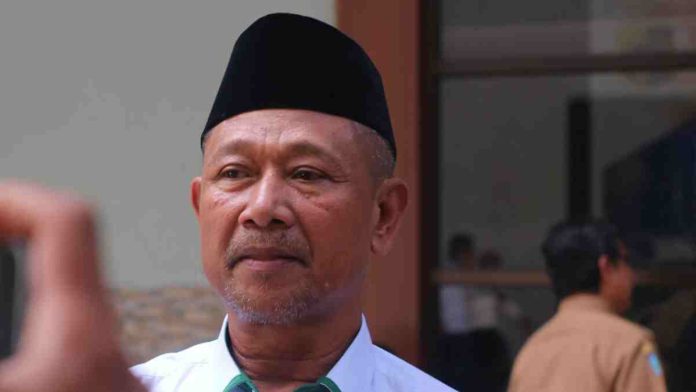 Kepala Kantor Kemenag Lombok Timur H. Sulhi mengenakan peci hitam dan kemeja putih saat memberikan pernyataan pers terkait kasus hukum pimpinan Ponpes Sukamulia.