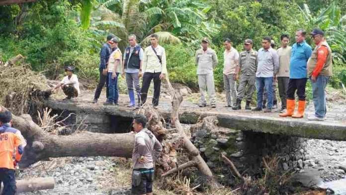 Logopit_1771665686692_2 Gubernur NTB Lalu Muhamad Iqbal bersama rombongan meninjau jembatan rusak akibat banjir di Lombok Timur yang terhalang batang pohon besar tumbang.