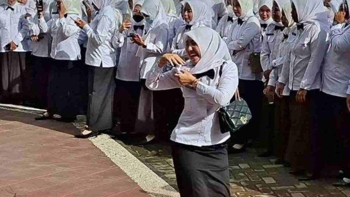 Seorang guru perempuan berseragam putih hitam tampak berjoget bahagia merayakan penerimaan SK PPPK di Lombok Timur.
