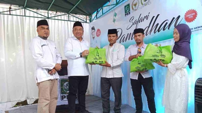 H. Lalu Hadrian Irfani berbaju putih menyerahkan bungkusan hadiah berwarna hijau kepada warga di atas pentas acara Safari Ramadhan bertemakan simbol PKB.