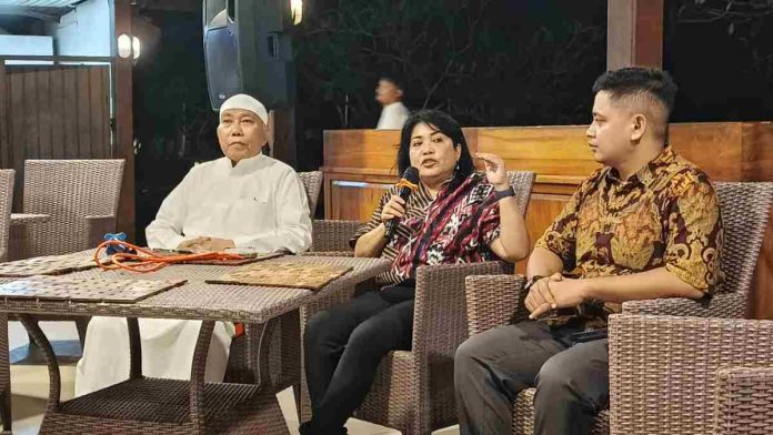Tiga orang narasumber duduk di kursi rotan dalam sebuah pertemuan formal; narasumber wanita di tengah memegang mikrofon sedang memberikan penjelasan terkait kebijakan Badan Gizi Nasional.