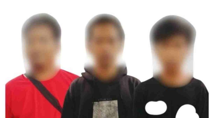 Sebuah foto polisi yang menampilkan tiga orang pria terduga pelaku kejahatan dengan wajah diburamkan (blurred) sedang berdiri berjejer, satu mengenakan kaos merah dan dua lainnya berkaos hitam.
