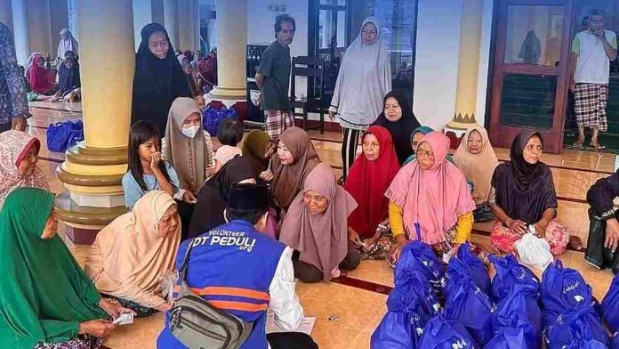 Seorang relawan laki-laki dengan rompi biru bertuliskan 