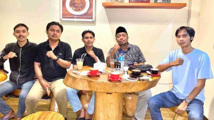 duduk mengelilingi meja kayu di sebuah kafe, sebahagian daripada mereka mengepalkan tangan sebagai simbol sokongan terhadap penegakan hukum.