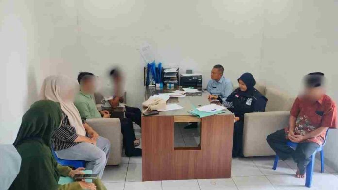 Tiga orang petugas BBPOM dengan seragam dinas sedang duduk mengelilingi meja, meneliti sampel roti kukus yang diduga tidak layak konsumsi untuk diperiksa kualitas keamanan pangannya.