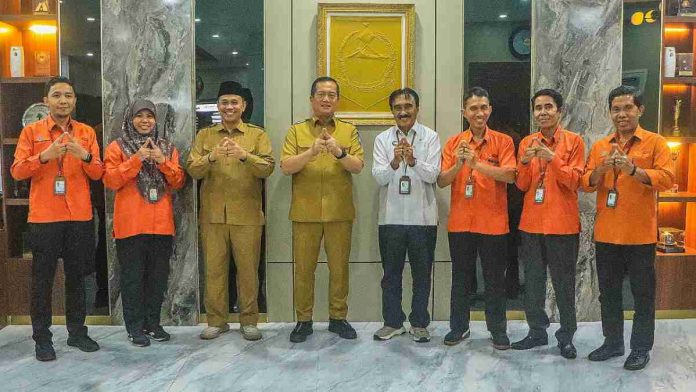 Foto bersama Gubernur NTB Lalu Muhamad Iqbal (baju cokelat) dengan Kepala BPS NTB dan tim pendata yang mengenakan seragam oranye di ruang tamu utama Kantor Gubernur, sambil berpose simbolis.