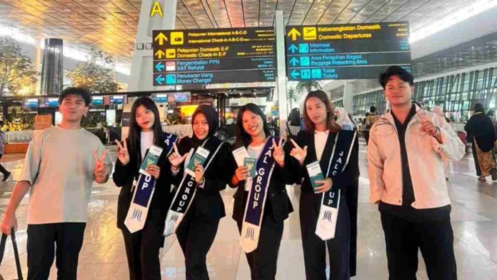 Foto bersama enam orang pemuda-pemudi Indonesia, calon tenaga kerja PT ARK Jinzai, di terminal keberangkatan bandara. Empat wanita mengenakan selempang bertuliskan logo perusahaan dan memegang paspor.