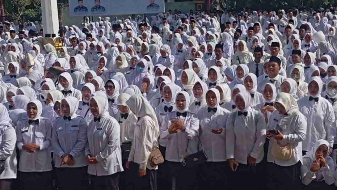 Kerumunan besar ratusan tenaga kerja berseragam putih dengan dasi kupu-kupu hitam, didominasi perempuan berhijab putih, sedang berdiri merapat dalam sebuah pertemuan terbuka.