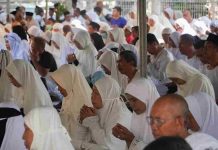 TGH Mujiburrahman Tutup Manasik Haji Mataram Ingatkan Jaga Lisan Deretan jemaah calon haji pria dan wanita mengenakan pakaian serba putih serta peci hitam sedang duduk bersila dan berdoa bersama dalam sebuah tenda besar.