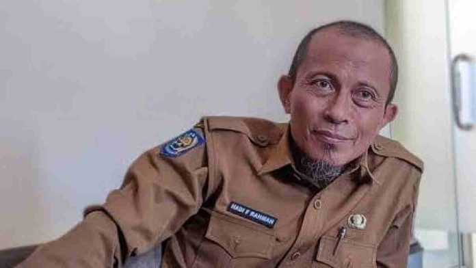 Foto potret Kepala Dinas Perdagangan Lombok Timur, Hadi Fathurahman, mengenakan seragam dinas cokelat (ASN) sedang duduk memberikan keterangan di dalam ruangan kantor.