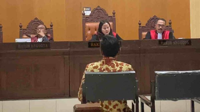 Suasana persidangan di Pengadilan Tipikor Mataram yang memperlihatkan saksi Nursalim tampak belakang mengenakan kemeja batik, duduk menghadap majelis hakim yang terdiri dari tiga orang.