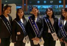 Lima Pejuang Kaigo PT ARK Jinzai Solusi Group Berangkat ke Jepang Lima wanita muda berdiri berjajar mengenakan seragam jas hitam dan kaus putih. Masing-masing mengenakan selempang biru tua bertuliskan "JAL GROUP" dengan logo perusahaan di bagian bawah. Mereka berpose di dalam area terminal bandara dengan ekspresi tersenyum siap berangkat.