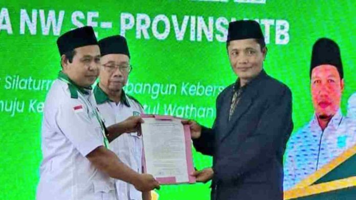 Dua pria berdiri berhadapan di atas panggung dengan latar belakang layar hijau bertuliskan 