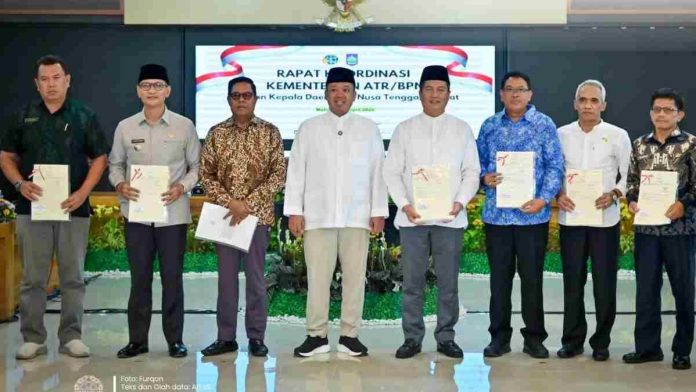 Penyerahan-Sertipikat-Aset-Kota-Mataram-Menteri-ATR-BPN Sembilan pria berdiri berjejer di dalam aula rapat dengan latar belakang layar digital bertuliskan