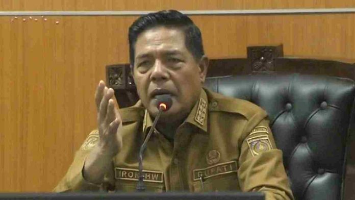 Tiga orang pria mengenakan toga advokat hitam dengan jabot putih duduk di kursi kayu berukir. Pria di depan bersedekap dengan ekspresi serius, sementara rekannya menyimak sambil memegang jam tangan.