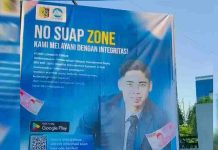 PDAM Lombok Timur Pasang Banner No Suap Zone dan Barcode Layanan Digital Spanduk biru besar bertuliskan "NO SUAP ZONE KAMI MELAYANI DENGAN INTEGRITAS" yang menampilkan foto Direktur PDAM Lombok Timur, logo aplikasi Google Play, dan kode QR untuk akses layanan digital