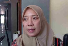 Mataram Protes Aturan Lahan Sawah 87 Persen Usulkan Opsi Berbagi Kuota Daerah Close-up wajah Lale Widiahning mengenakan hijab cokelat sedang berbicara memberikan keterangan pers kepada wartawan di lorong sebuah gedung.