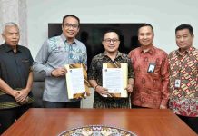 Bank NTB Syariah Perkuat Digitalisasi SP2D Online Lombok Tengah Lima pria mengenakan batik berdiri formal di ruang rapat. Dua orang di tengah tersenyum sambil memegang map dokumen perjanjian yang telah ditandatangani.