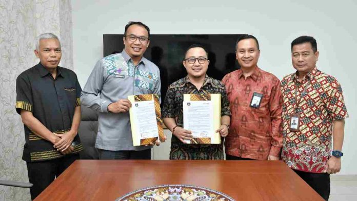Lima pria mengenakan batik berdiri formal di ruang rapat. Dua orang di tengah tersenyum sambil memegang map dokumen perjanjian yang telah ditandatangani.