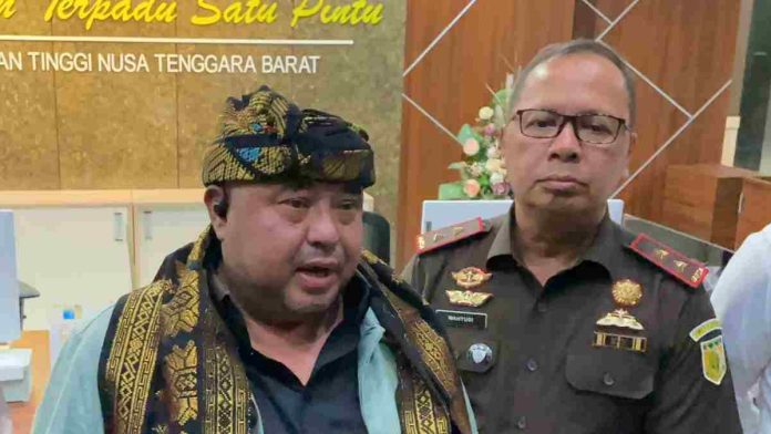 Habib Aboe Bakar Al-Habsyi mengenakan udeng tradisional dan selendang songket sedang berbicara didampingi pejabat Kejaksaan Tinggi NTB berseragam cokelat.