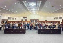 Milad Perdana FKAK NTB Jadi Momentum Penguatan Mitra Kritis Kesehatan Foto grup puluhan pemuda dan tokoh kesehatan berdiri berjajar di dalam aula besar dengan pencahayaan terang, berpose mengepalkan tangan sebagai simbol semangat organisasi.