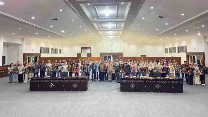 Foto grup puluhan pemuda dan tokoh kesehatan berdiri berjajar di dalam aula besar dengan pencahayaan terang, berpose mengepalkan tangan sebagai simbol semangat organisasi.