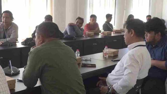 Sejumlah pria sedang duduk serius dalam ruang rapat formal, memperhatikan jalannya diskusi antara anggota DPRD, pihak perbankan, dan perwakilan nasabah.