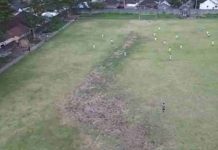 Warga Kota Raja Lombok Timur Sulap Lapangan Kumuh Jadi Arena Standar Liga 3 Foto udara lapangan sepak bola dengan rumput hijau yang tidak merata, menunjukkan beberapa titik tanah gersang dan pemain bola sedang beraktivitas di lapangan.