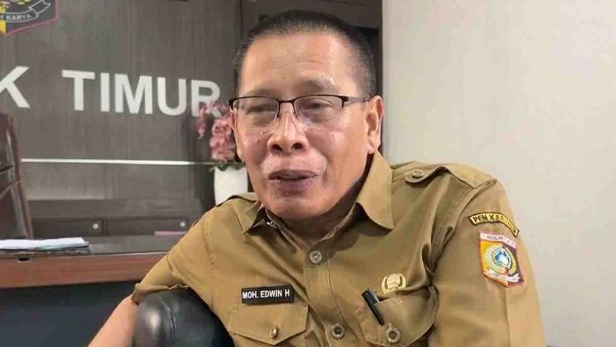 Foto close-up Wakil Bupati Lombok Timur Moh. Edwin Hadiwijaya mengenakan seragam dinas cokelat (KHAKI) sedang berbicara memberikan penjelasan resmi di depan kamera.