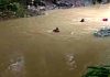 Tragedi Bola di Tepian Sungai, Remaja Kuripan Hanyut Terbawa Arus Deras Tiga orang personel tim SAR mengenakan helm dan pelampung oranye sedang berenang menyisir sungai yang berwarna cokelat keruh dengan arus cukup kuat.