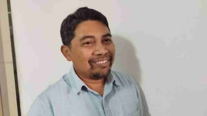 Empat pria duduk melingkar di meja rapat studio TV dengan latar belakang layar besar peta dunia biru, sedang melakukan diskusi formal atau audiensi.