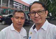 RSUD Soedjono Selong Siap Sukseskan Event Rinjani 100, Akan Siagakan Tim Medis di 6 Pos Dua pria berseragam dinas putih berdiri di area parkir dengan latar belakang gedung RSUD dr. R. Soedjono Selong yang memiliki atap merah dan fasad modern.