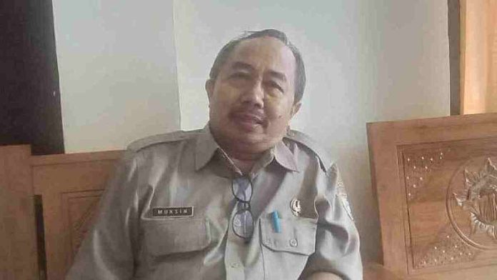 Bupati Haerul Warisin memakai jaket hijau gelap dan kacamata hitam sedang menyalami warga di lokasi terbuka, didampingi staf BPBD berseragam putih dan topi oranye.