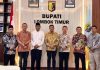 Jamkrida NTB Syariah Gandeng Pemda Lombok Timur Pacu PAD dan Ekonomi UMKM Bupati Haerul Warisin berdiri bersama jajaran direksi Jamkrida NTB Syariah di ruang kerja bupati, tampak kompak mengenakan kemeja batik dan peci hitam.