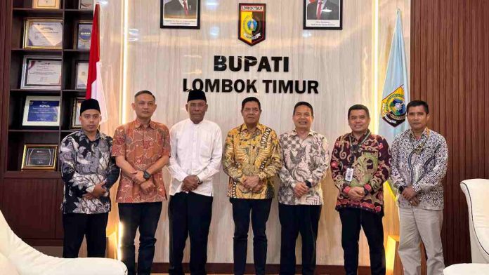 Bupati Haerul Warisin berdiri bersama jajaran direksi Jamkrida NTB Syariah di ruang kerja bupati, tampak kompak mengenakan kemeja batik dan peci hitam.
