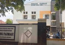 Serangan ISPA di Lombok Timur Capai 1.500 Kasus Setiap Pekan Tampak depan gedung bertingkat Gudang Farmasi Dinas Kesehatan Kabupaten Lombok Timur dengan pagar hitam dan papan nama instansi yang jelas di bagian depan.