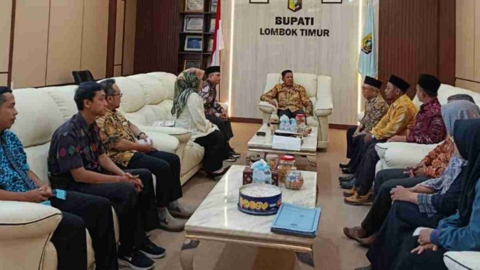 Bupati Haerul Warisin duduk di kursi sofa putih memimpin pertemuan dengan delegasi KI NTB yang duduk berhadapan di ruang tamu pendopo kabupaten.