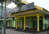 Bank NTB Syariah Respons Cepat Laporan Nasabah di Cabang Dompu Tampak depan bangunan kantor Bank NTB Syariah KC Dompu berwarna hijau dengan aksen pilar kuning, dilengkapi papan nama besar di bagian atas serta pepohonan di halaman.
