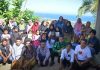 Rayakan Hardiknas di Pelosok Lombok Tengah, Tastura Mengajar Suarakan Ketimpangan Akses Pendidikan Foto bersama komunitas Tastura Mengajar dengan puluhan warga desa dan anak-anak di sebuah perbukitan dengan latar belakang pemandangan laut serta garis pantai yang biru di Lombok Tengah.