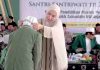 Ketum PBNW Ingatkan Santri NW Anjani Jaga Almamater di Acara Penamatan Seorang wanita berhijab krem sedang mengalungkan medali kepada seorang santri yang membungkuk, dengan latar belakang tamu undangan dan spanduk acara.