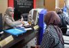 Mantap! Urus Roya di Kabupaten Semarang Kini Hanya Butuh Lima Menit Petugas wanita berhijab di loket Kantor Pertanahan sedang melayani pemohon, tampak latar belakang bertuliskan Badan Pertanahan Nasional Kabupaten Semarang.
