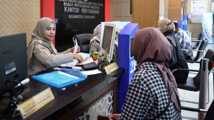Petugas wanita berhijab di loket Kantor Pertanahan sedang melayani pemohon, tampak latar belakang bertuliskan Badan Pertanahan Nasional Kabupaten Semarang.