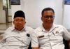 Ketua FKKD Lotim Ancam Segel KUA Masbagik, Kemenag Klaim Masih Tunggu Pusat Foto dua pria duduk berdampingan di dalam ruangan; pria di sebelah kanan (M. Haerul Ikhsan) mengenakan kemeja putih dan kacamata, sementara pria di sebelah kiri mengenakan kopiah hitam.