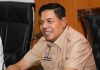 Bupati Lombok Timur Dorong Hilirisasi Porang dan Penguatan Desa Berdaya Bupati Lombok Timur H. Haerul Warisin mengenakan seragam dinas cokelat, sedang berbicara dengan ekspresi serius di depan mikrofon dalam sebuah pertemuan resmi.