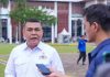 Wamen ATR Ossy Dermawan Ancam Sanksi Pemegang HGU yang Bakar Lahan Wakil Menteri ATR Ossy Dermawan mengenakan kemeja putih berlogo kementerian, sedang berbicara di depan wartawan di sebuah lapangan terbuka.