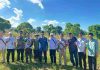Petani Lombok Timur Naik Kelas Jadi Muzakki Berkat Lumbung Pangan Baznas Sepuluh orang pria berdiri berjejer di lahan pertanian jagung yang luas dengan latar belakang langit biru cerah, menunjukkan pose kebersamaan usai panen.
